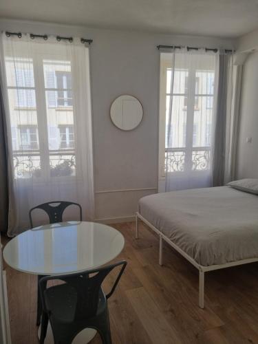 une chambre avec un lit et une table et deux fenêtres dans l'établissement Chambre privée - Vue Tour Eiffel, à Paris