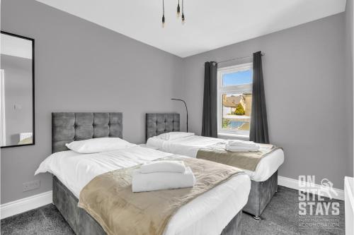 a bedroom with two beds and a window at OnSiteStays - Large 3 bedroom, 2 bathroom, driveway, Garden, Sleeps 6 Comfortably in Bexleyheath