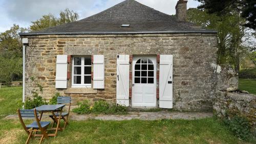 an old stone house with white doors and a table at Gîte de couple Cosy avec vue sur Château Trémohar - Golfe du Morbihan, 20 min de Vannes in Berric