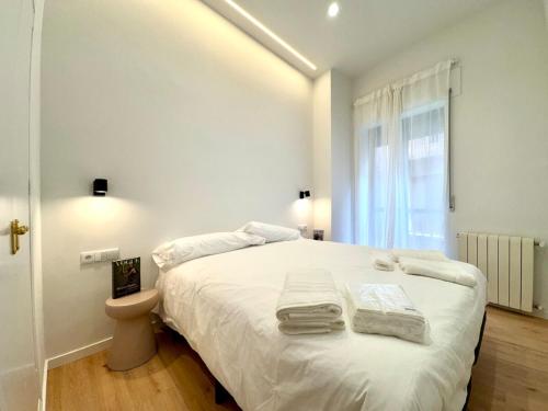 een witte slaapkamer met een bed met handdoeken erop bij Azahar Homes - Murcia Centro in Murcia