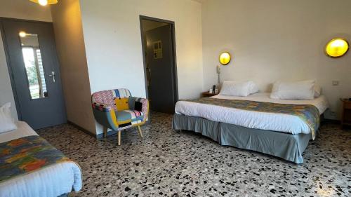 a hotel room with two beds and a chair at Logis Hotel Eden Lac in Savines