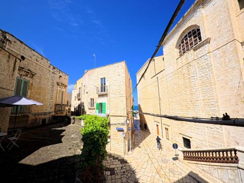 an alley with two stone buildings and an umbrella at Palazzo Framarino dei Malatesta - Noble Floor - XIV Century in Giovinazzo