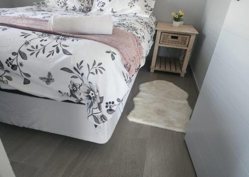 Un dormitorio con una cama con un edredón blanco y negro. en Arum Cove Bloubergstrand, en Cape Town