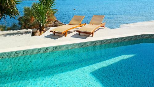 two chairs and a swimming pool next to the ocean at Porto Evia Boutique Hotel in Amarinthos