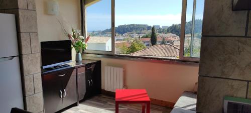 un salon avec une télévision et un fauteuil rouge dans l'établissement Charmant 2 pièces vue mer et château et parking, à Villeneuve-Loubet