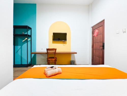 a bedroom with a bed and a desk with a television at Sans Salmas Mojokerto in Kranggan