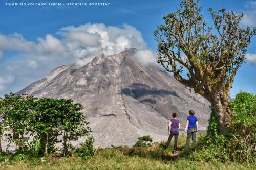two people standing in front of a mountain at Nachelle Homestay in Berastagi