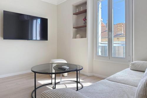 un salon avec une table en verre et une télévision dans l'établissement Le Montfleury 2 pièces à 300m de la plage, à Cannes