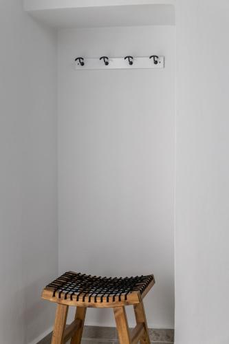 a wooden stool sitting in front of a white wall at Melian Roots Studio in Adamas