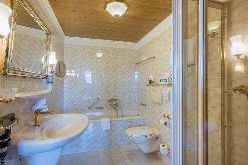 a bathroom with a tub and a sink and a toilet at Landhotel Gockelwirt in Eisenberg
