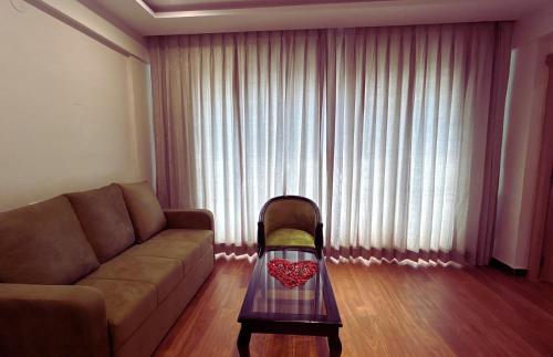 a living room with a couch and a table in front of a window at Serene Resort Hyderabad in Shamshabad