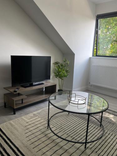 Una sala de estar con televisión y una mesa de centro de cristal. en Royal Oak 7 - FREE PARKING - Sleeps 5 - Perfect for Contractors - Near Shops - Wi-Fi - Long Term Stays, en Brentwood
