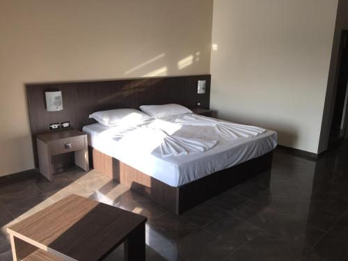 a bedroom with a large bed with a wooden headboard at Herges Hotel in Durrës