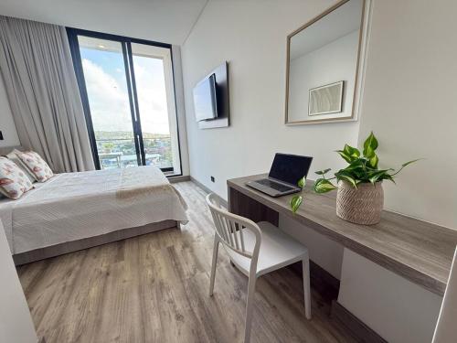 a bedroom with a bed and a desk with a laptop at Almare Apartamentos nuevos in Gustavo Rojas Pinilla International
