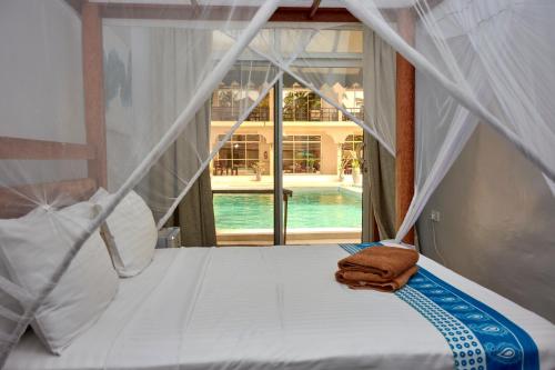 a bedroom with a bed with a view of a pool at Paje Beach Apartments & Hotel in Paje