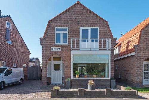 a brick house with a white door in a parking lot at Le Paysan in Wijk aan Zee