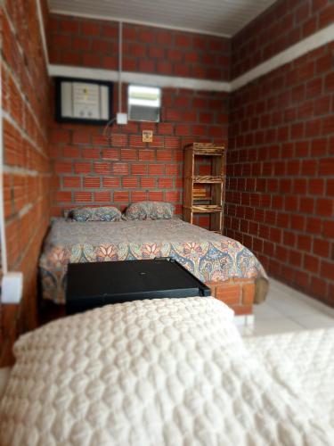 a bedroom with two beds and a brick wall at Chalé cantinho do ceu in Santo Amaro