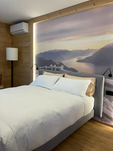 a bedroom with a large white bed with a painting on the wall at Da Gigi Alpine Rooms in Crandola Valsassina