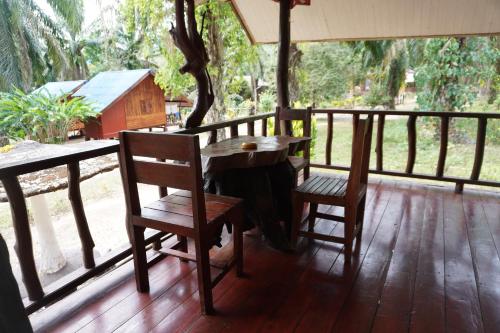 a wooden table and two chairs on a porch at Khao Sok Palmview Resort in Khao Sok