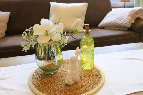 a table with a vase and a figurine of a bunny and a bottle at Ferienwohnung Ostersander - zentral gelegen zwischen Ihlow, Timmeler Meer, Aurich und der Wassersportanlage in Tannenhausen in Ihlow