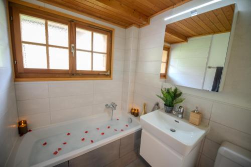 a bathroom with a tub and a sink and a mirror at Chalet aux Portes du Soleil avec balcon in Val-d'Illiez