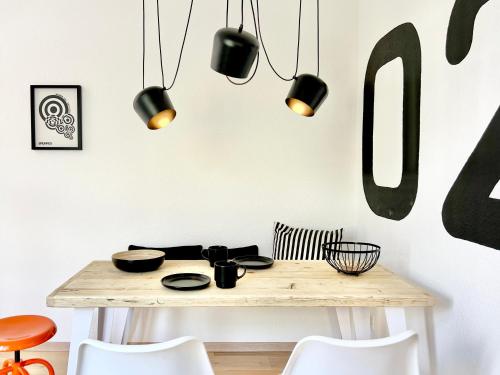 a kitchen with a wooden table and black pendant lights at Neu MAKERS and ROOMS APARTMENTS Rosental am Schlosspark Detmold in Detmold