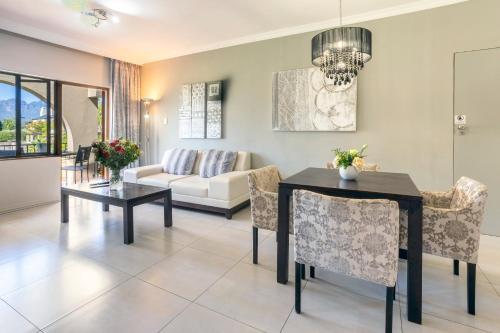 a living room with a table and chairs and a couch at Devonvale Golf & Wine Estate in Stellenbosch