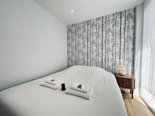 1 Schlafzimmer mit einem weißen Bett und 2 Handtüchern in der Unterkunft 2 Lenoir T2 spacieux avec jacuzzi au centre-ville in Reims