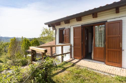 a small house with wooden doors and a deck at La Valle Dei Caprioli Village Bungalow Park - Freelandia Azienda Agricola in Montescudo