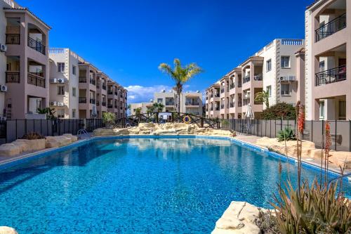 a swimming pool in the middle of two apartment buildings at Royal Seacrest amazing location 2 Bed Apartment by VICHY Holidays in Paphos