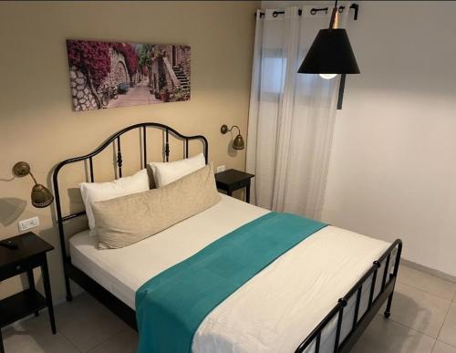 a bedroom with a bed with a green and white blanket at Welcome to Sunshine in Migdal