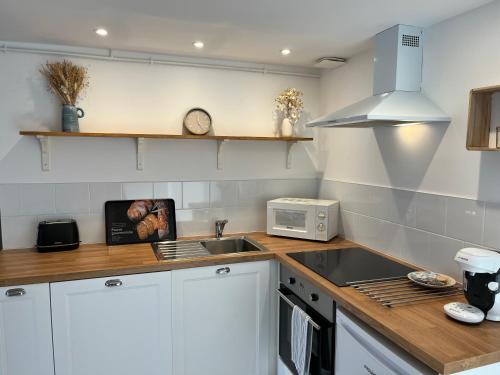 une cuisine avec des armoires blanches, un évier et un micro-ondes dans l'établissement Maison Baie du Mont St Michel, à Roz-sur-Couesnon