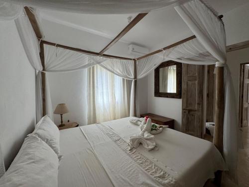 a bedroom with a white bed with a canopy at Casa Sanaa - Sea view in Watamu