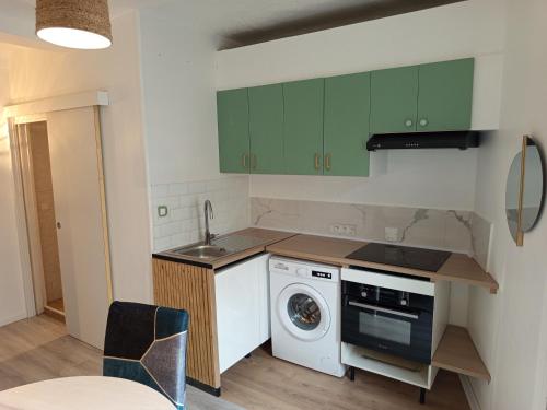 une cuisine avec des armoires vertes et une machine à laver dans l'établissement Calme, confortable et bien placé, à Nice