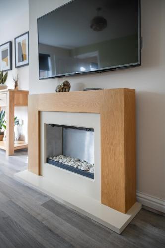 a living room with a fireplace with a tv above it at 3-Bed Home Near Town Center in Stirling