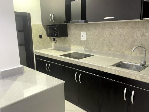 a kitchen with black cabinets and a sink at Seven kings apartment Lekki in Araromi