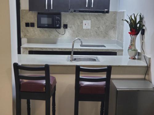 a kitchen with two bar stools and a sink at Seven kings apartment Lekki in Araromi
