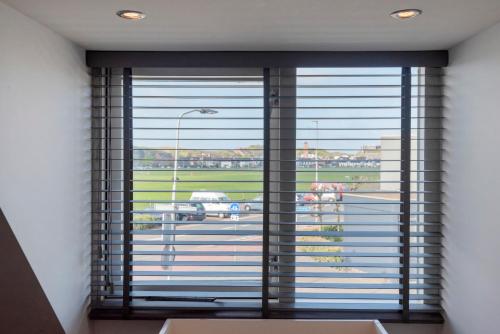 a large window with a view of a parking lot at Wijkiki Surf House in Wijk aan Zee