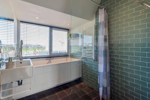 a bathroom with a tub and a sink and a window at Wijkiki Surf House in Wijk aan Zee