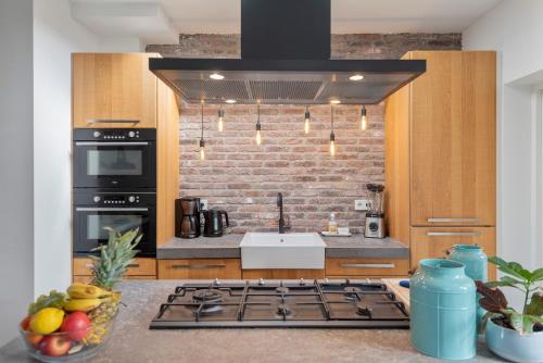 a kitchen with a stove and a brick wall at Wijkiki Surf House in Wijk aan Zee