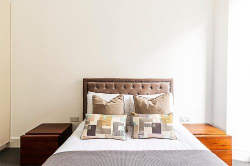 a bedroom with a bed with pillows and a table at Harley Street Luxury Apartments by City Relay in London