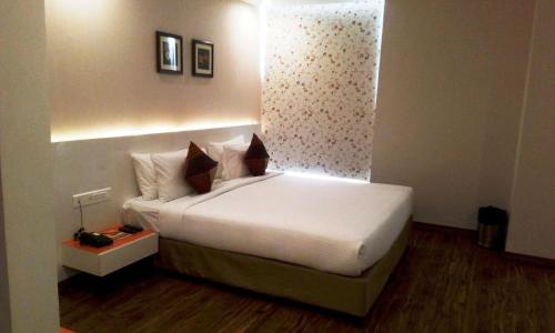 a bedroom with a bed with white sheets and pillows at Mango Hotels Prangan in Bhubaneshwar