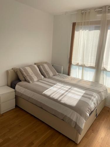 Ce lit se trouve dans un dortoir blanc doté d'une grande fenêtre. dans l'établissement Maison tout confort avec jardin à 35 min de Paris, à Arpajon