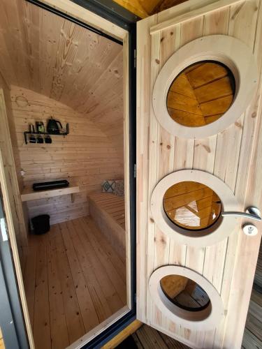 - un sauna en bois avec deux fenêtres circulaires et une porte dans l'établissement Le Cabanon du camping 2, à Bannes