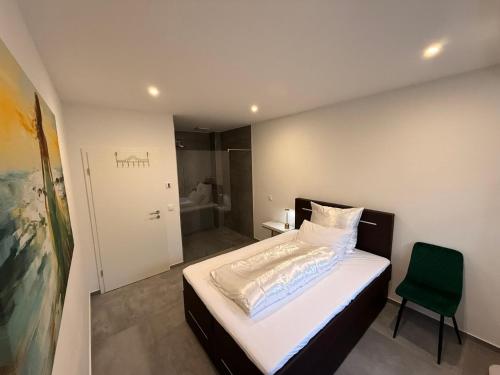 a bedroom with a bed and a green chair at Luxee Apartment in Friedrichshafen