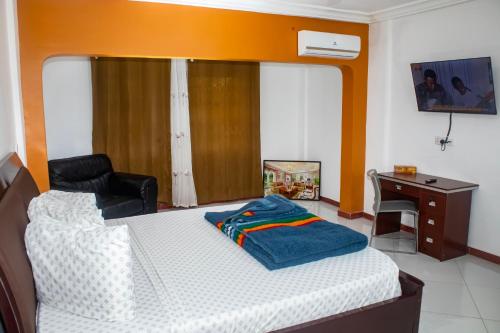 a bedroom with a bed with a desk and a chair at Park Springs Hotel in Cape Coast
