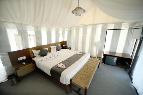 a bedroom with a large bed with white curtains at Badi Meadows in Udaipur