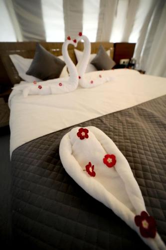 two beds with white towels with red flowers on them at Badi Meadows in Udaipur