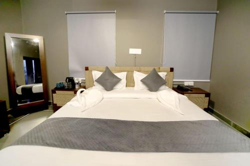 a bedroom with a large white bed with two windows at Badi Meadows in Udaipur