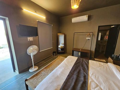 a bedroom with a bed with a fan and a window at Badi Meadows in Udaipur